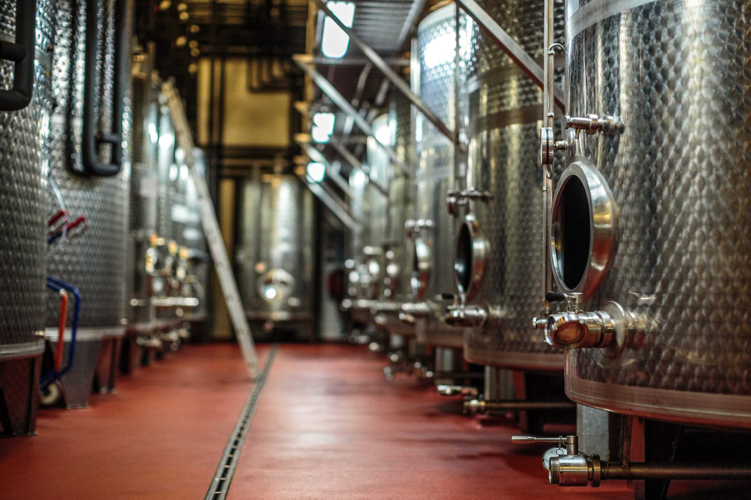 bryggeri med store fermenteringstanker i rustfritt stål på rødt epoxygulv